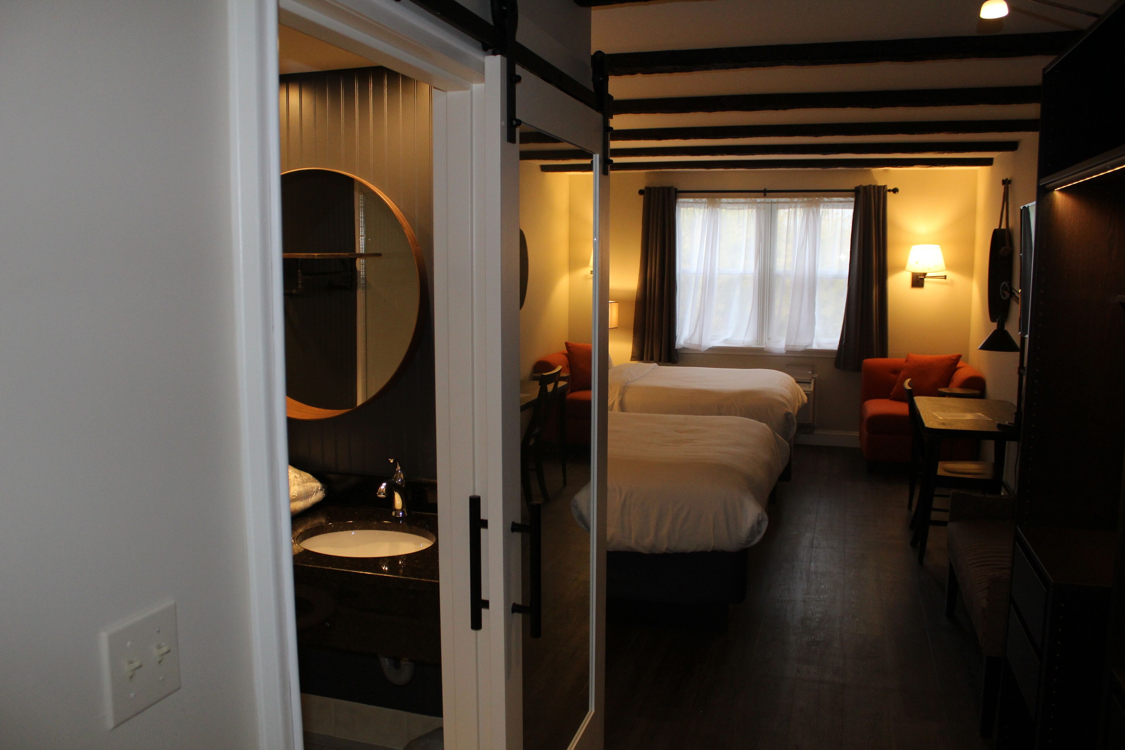 Une chambre d’hôtel avec un lit, une table de chevet, une lampe et une vue sur l’extérieur par une fenêtre.