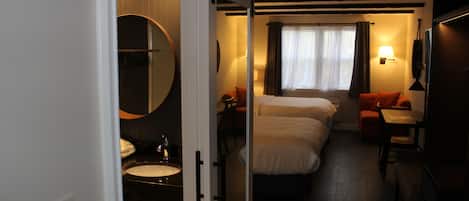 Une chambre d’hôtel avec un lit, une table de chevet, une lampe et une vue sur l’extérieur par une fenêtre.