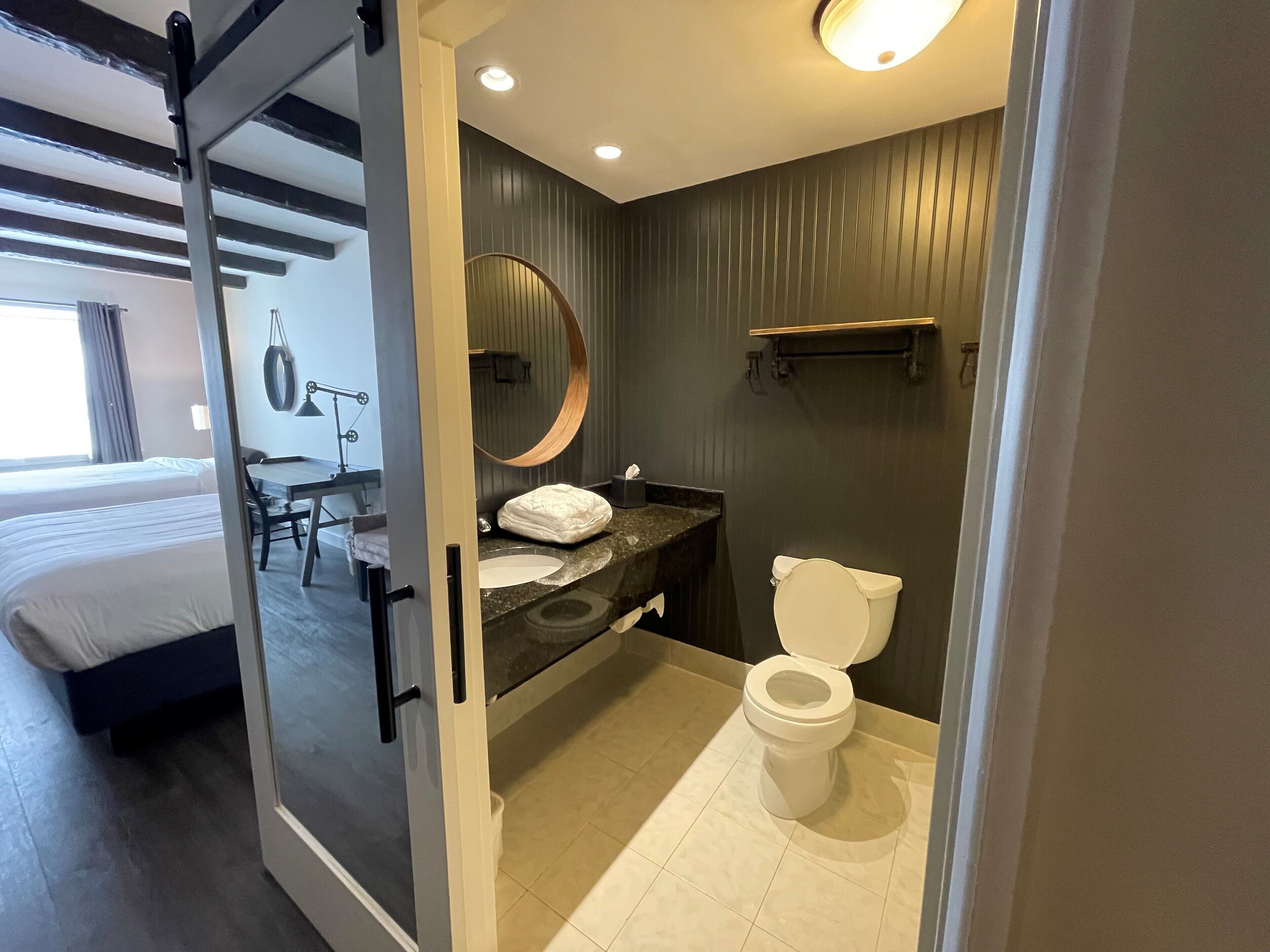 A modern hotel bathroom with a toilet, sink, and a large mirror.