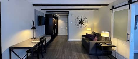 A modern living room with a dining area, a sofa, a coffee table, and a TV mounted on the wall.