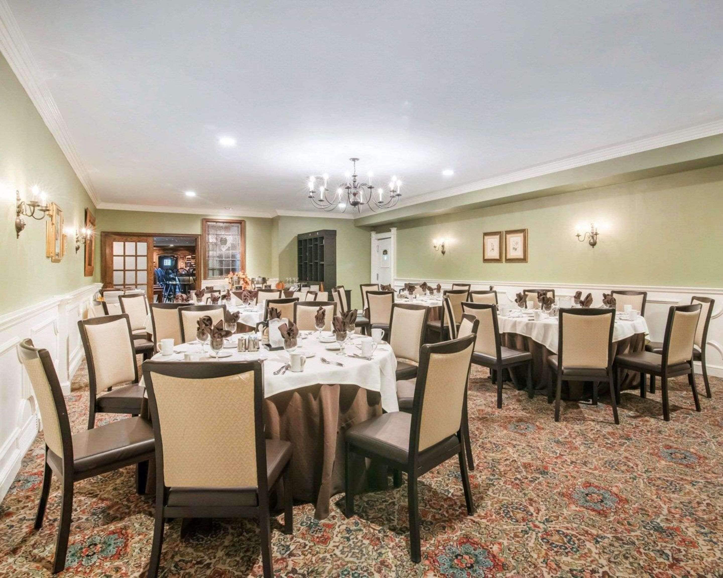A dining area with multiple tables and chairs, a patterned carpet, and a chandelier.