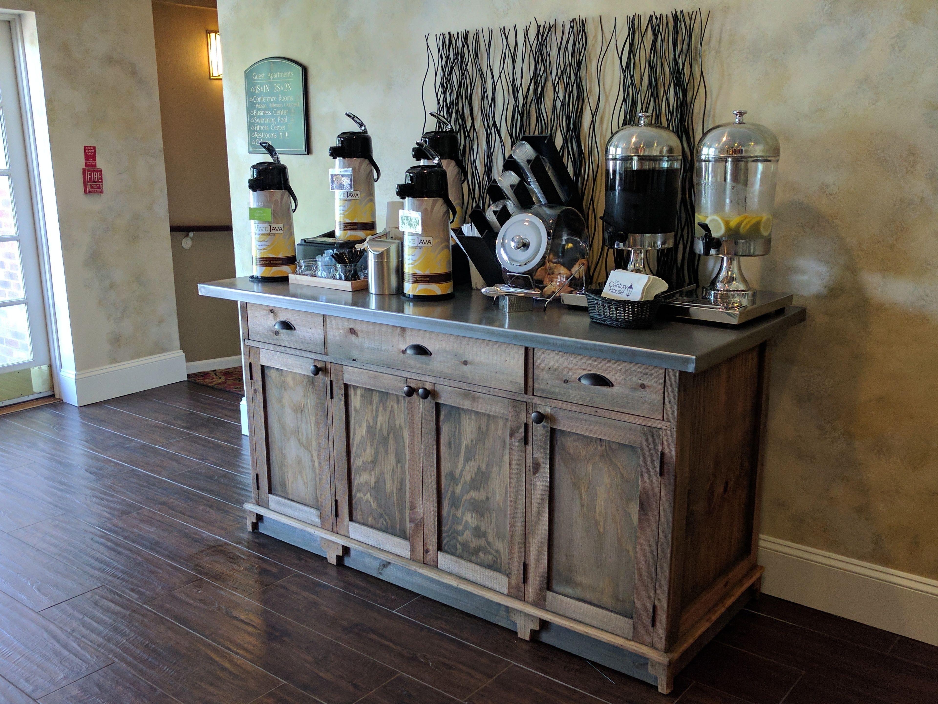 A wooden bar area with a coffee machine, a glass carafe, and a coffee grinder.