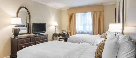 Habitación de hotel con dos camas, televisión, escritorio y ventana con cortinas.