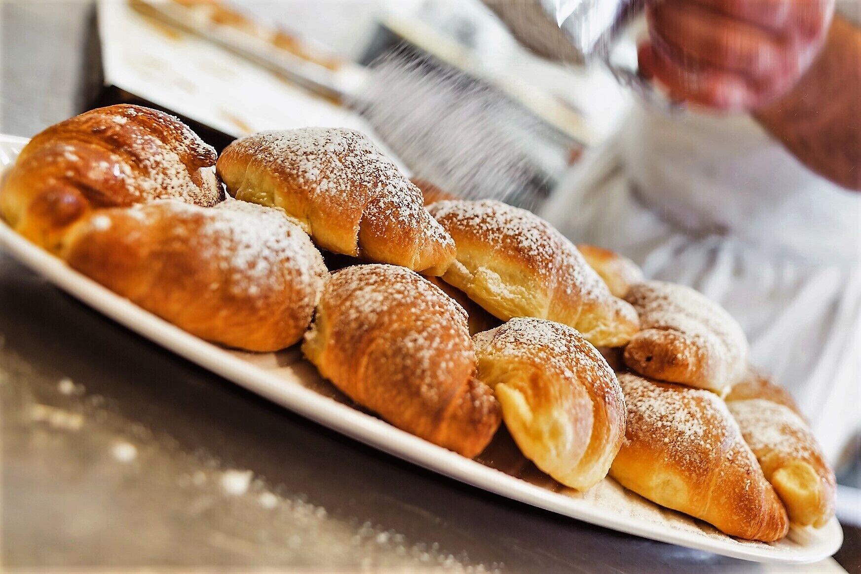 Um prato de croissants recém-assados polvilhados com açúcar de confeiteiro.
