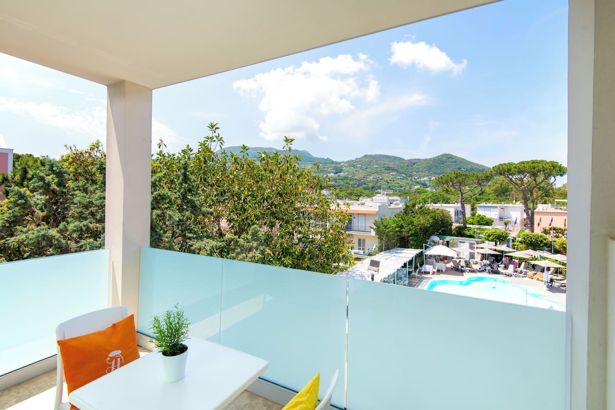 A balcony with a table, chairs, and a potted plant.