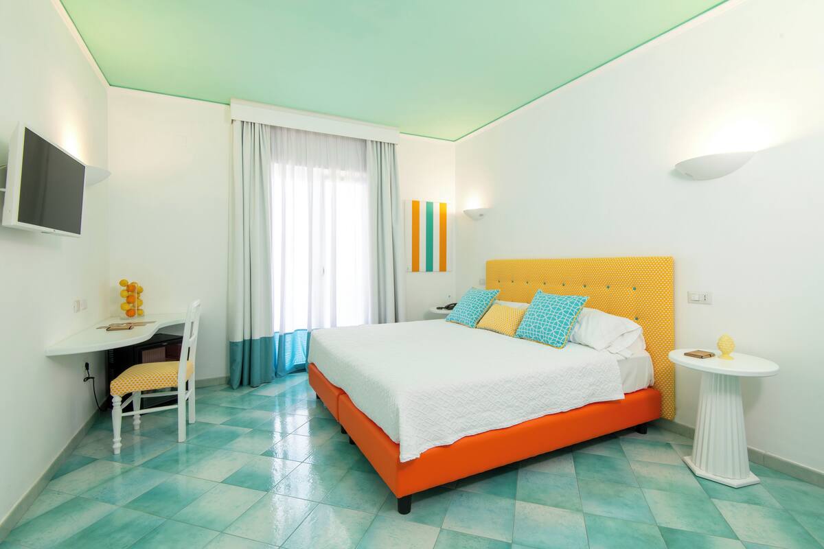 A bedroom with a bed, a desk, and a chair.