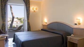 Habitación de hotel con cama, mesita de noche y vistas al exterior.