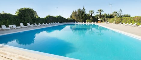 Una piscina al aire libre de temporada, sombrillas, tumbonas