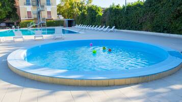 Relax by the pool surrounded by lounge chairs and a neatly trimmed hedge.