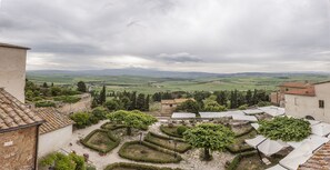 A courtyard with geometric garden paths, a central tree, and outdoor seating under white canopies. - Hotel Relais II Chiostro di Pienza (Pienza)