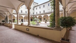 A spacious courtyard with arches, potted plants, and a fountain.
