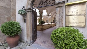 An entrance with a wrought iron gate, potted plants, and a plaque indicating the location as "Il Chistoro di Pienza Relais."