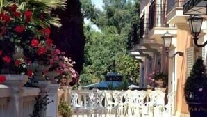A narrow outdoor corridor with white chairs and tables, surrounded by lush greenery and red flowers. - Hotel Villa Paradiso dell'Etna (San Giovanni la Punta)