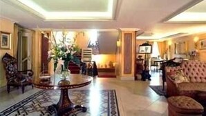 A spacious lobby with a round table, a sofa, and a chair. - Hotel Villa Paradiso dell'Etna (San Giovanni la Punta)