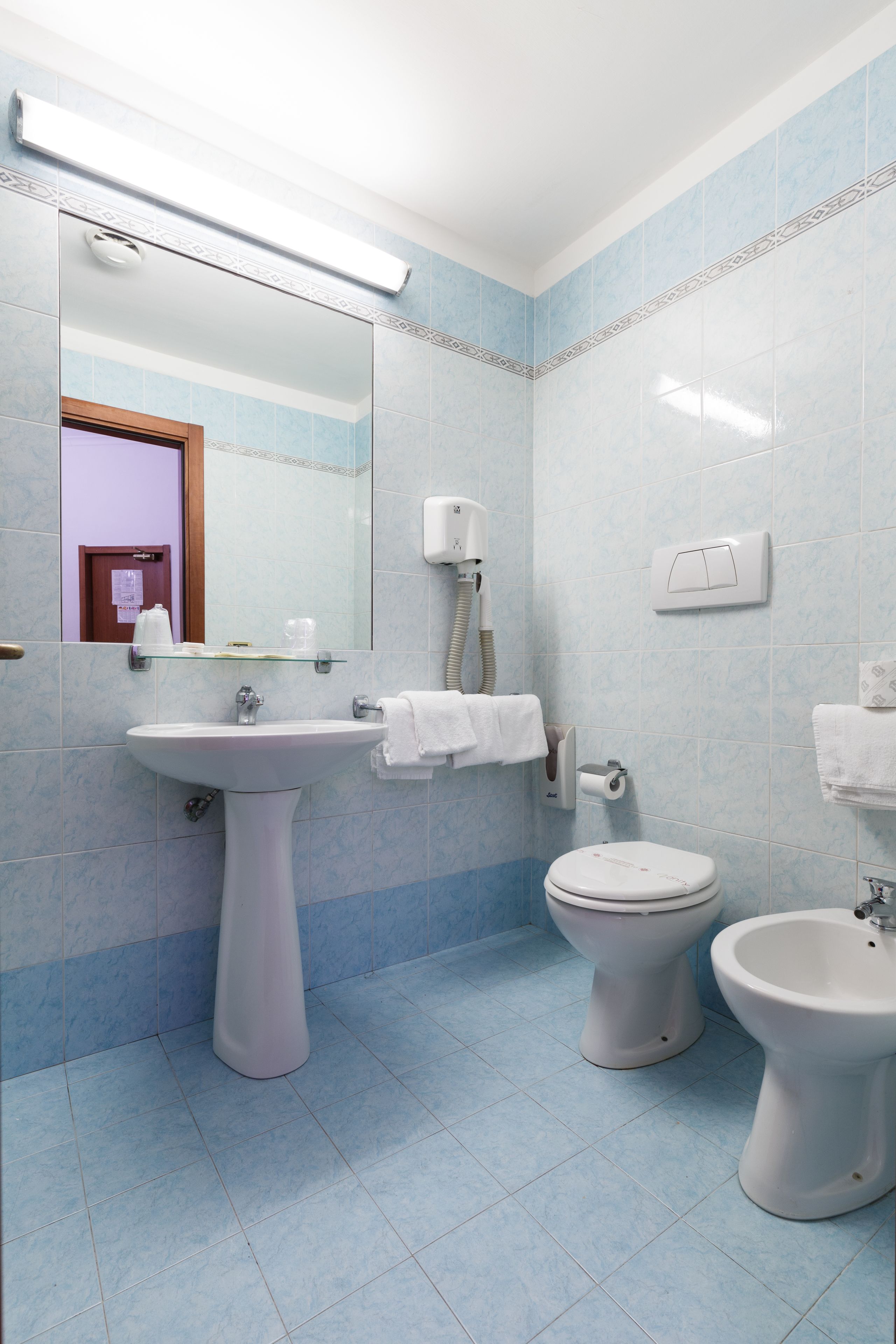 A bathroom with a pedestal sink, a toilet, and a bidet.