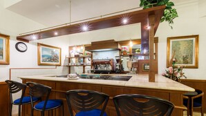 A bar area with wooden bar stools, a coffee machine, and a counter. - Hotel Paris (Rome)