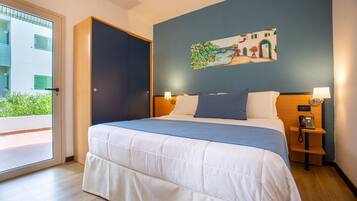 Habitación de hotel con una cama, un cuadro en la pared, una puerta y una mesita de noche con un teléfono.