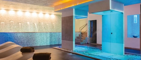 A modern spa area with a stone wall, a glass-enclosed water feature, and a staircase.