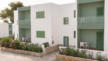 A modern building with balconies and a small patio area with outdoor seating.