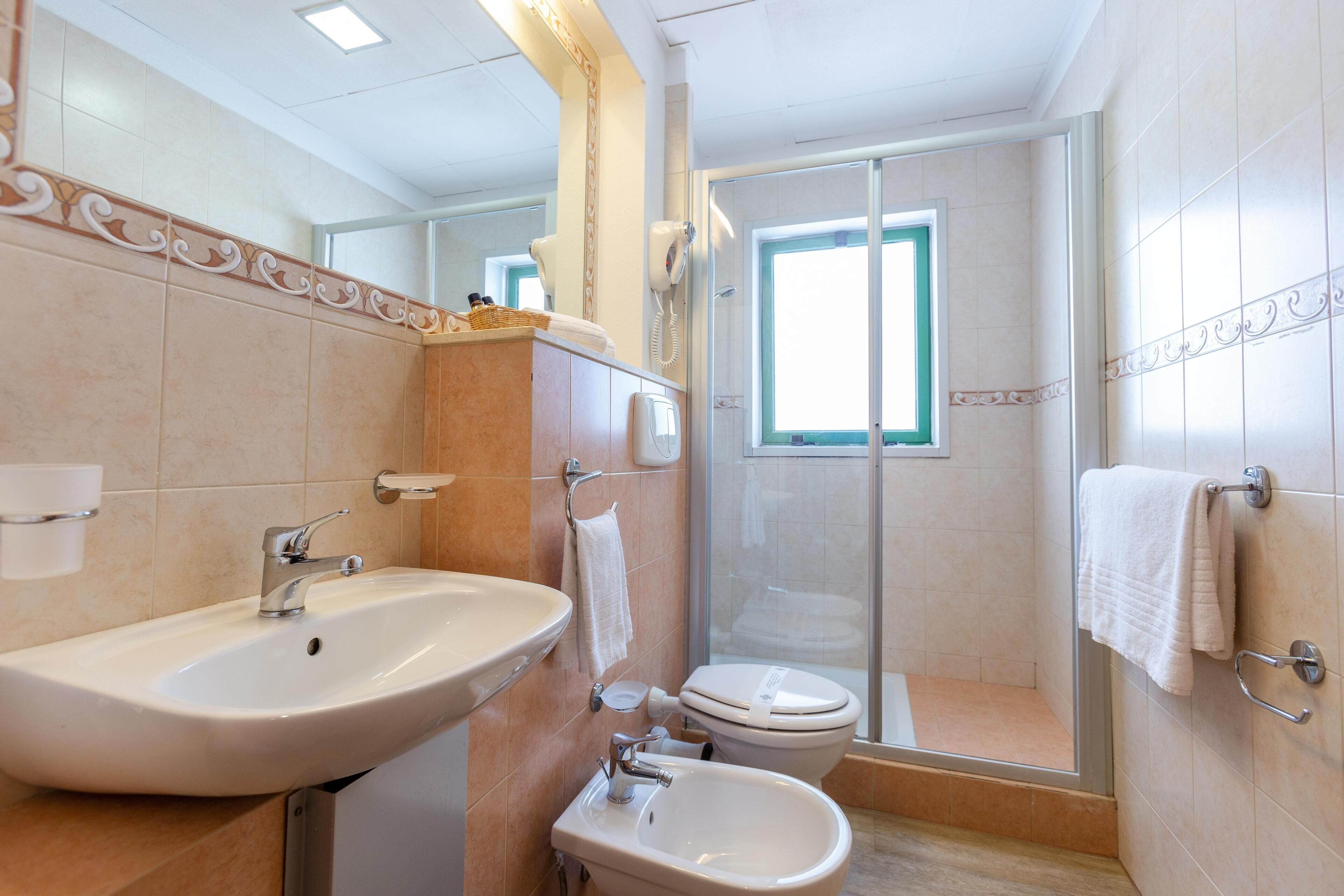 Une salle de bain moderne avec un grand lavabo, un bidet, des toilettes et une douche à parois de verre.