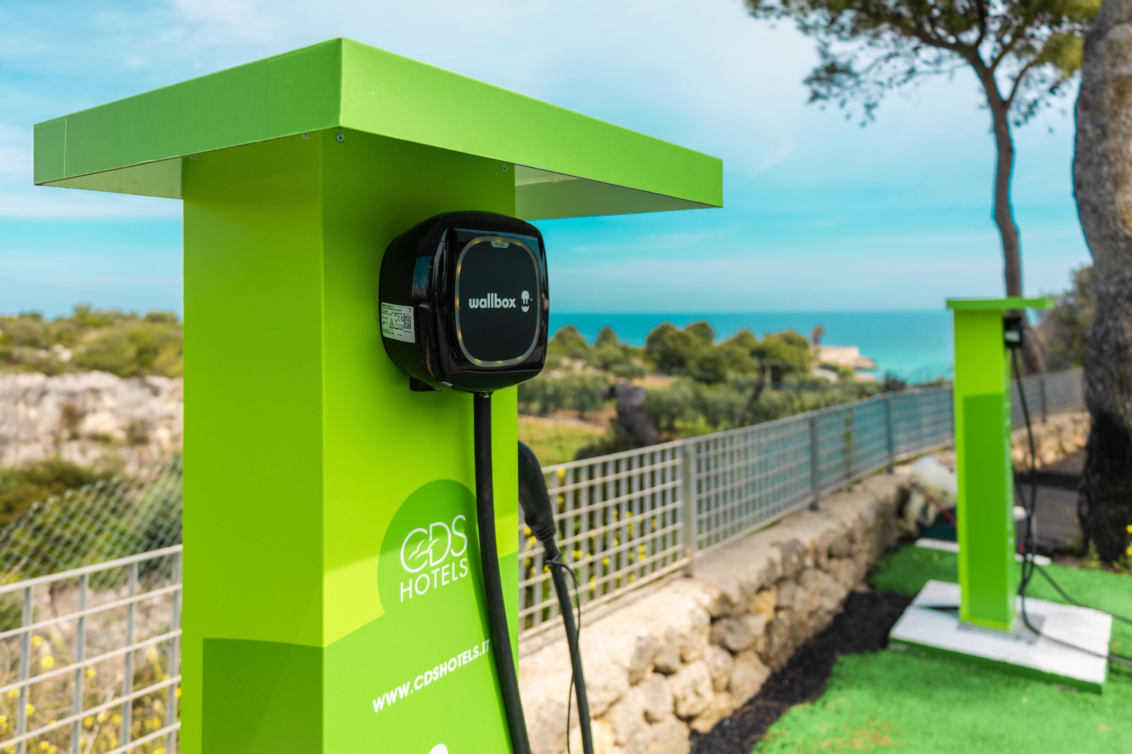 A green charging station with a black device labeled "wallbox" and the logo "CDS HOTELS" on a pillar.