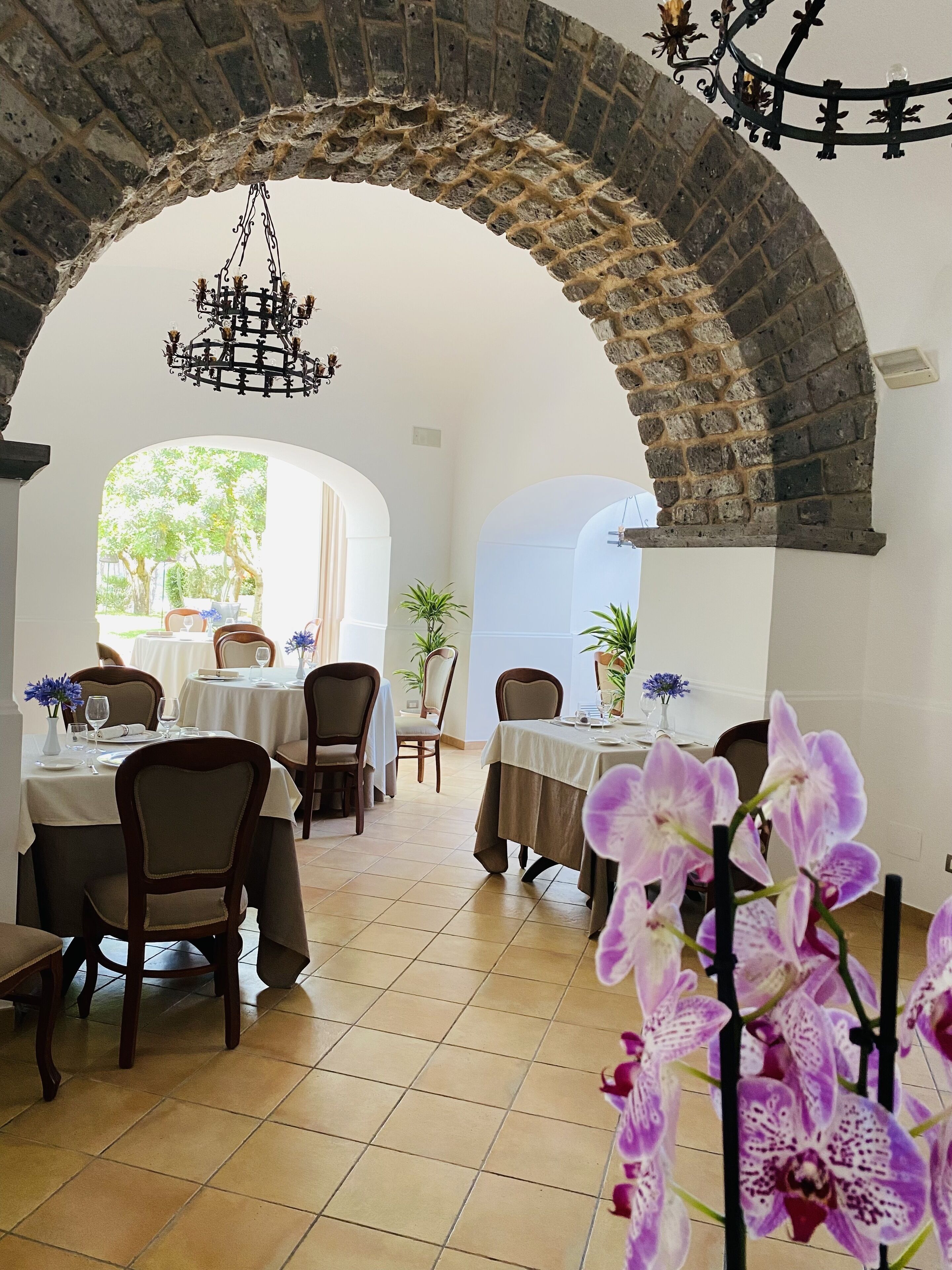 Comedor con mesas dispuestas para dos, bajo un arco de piedra.