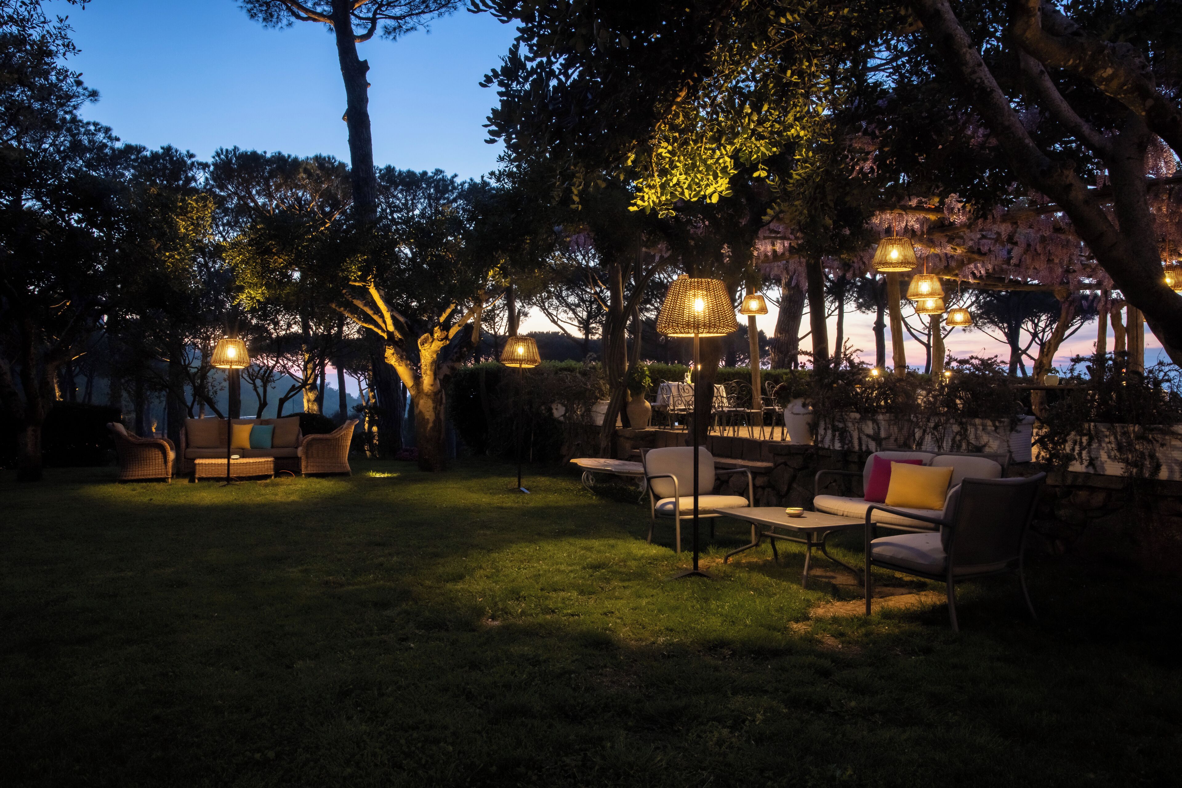 An outdoor seating area with wicker furniture and hanging lamps.