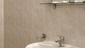 A bathroom with a white pedestal sink, a glass shelf above the sink, and a mirror on the wall. - Hotel Everest (Rome)