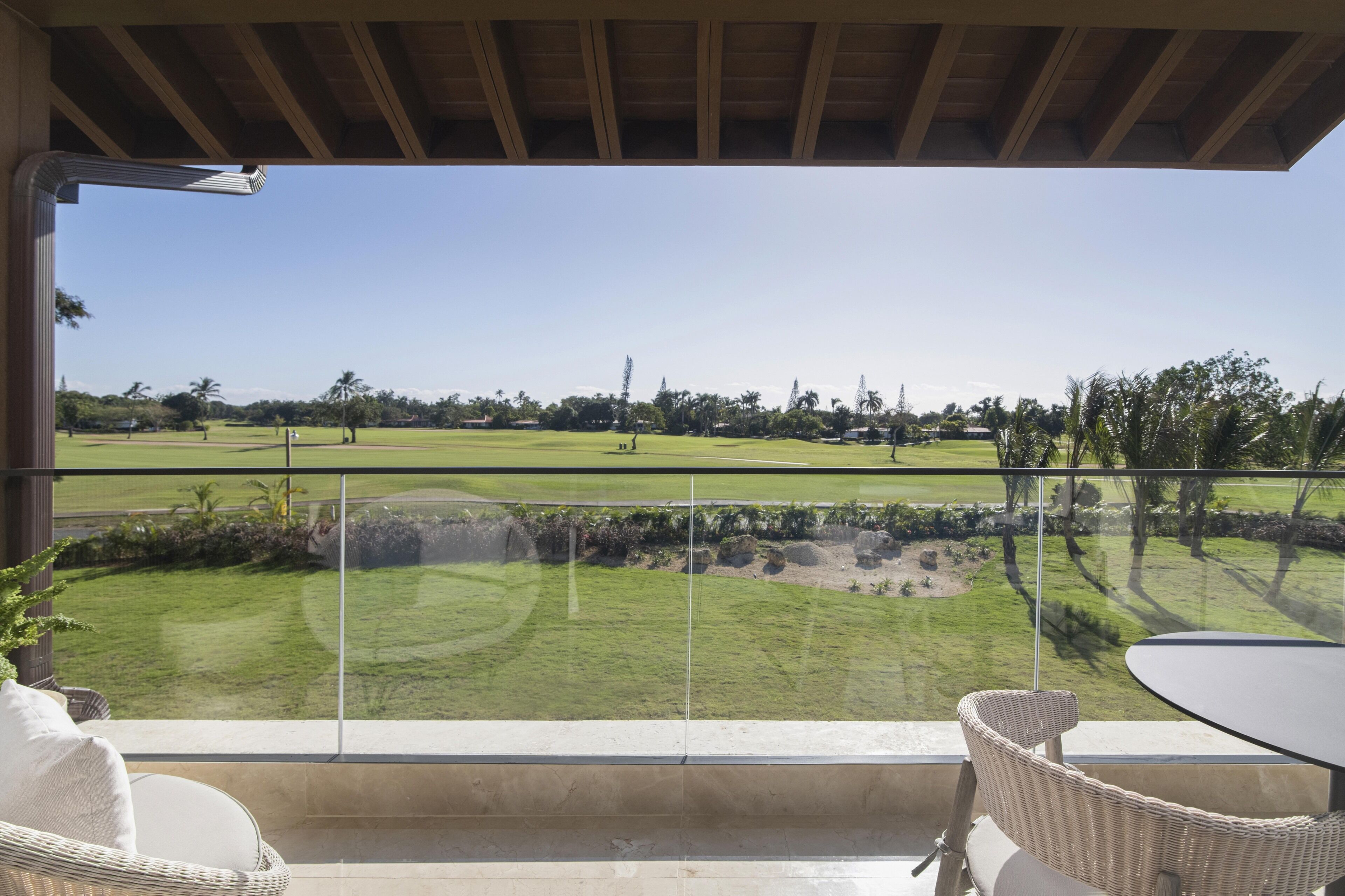 A balcony with wicker furniture and a clear view of a golf course.