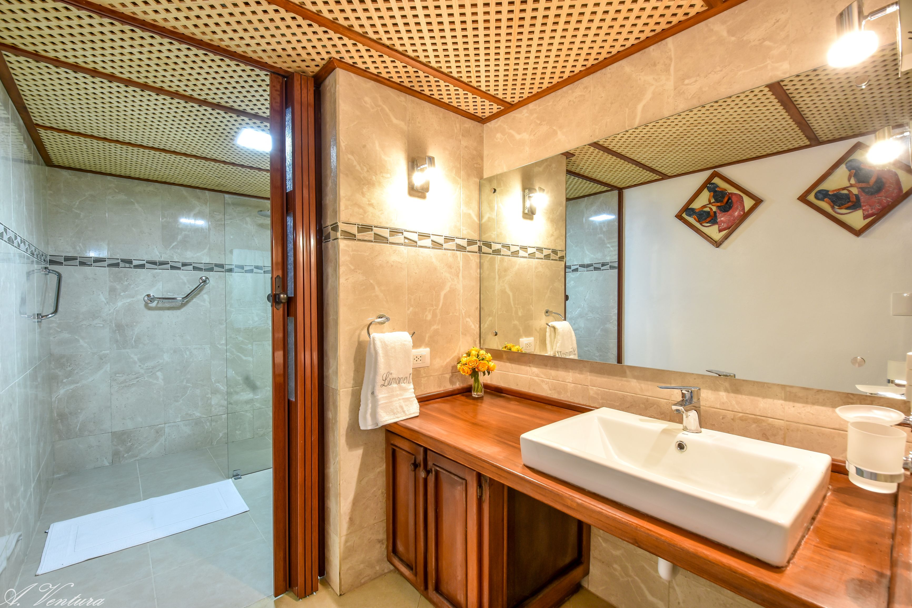 Un bany amb un mirall gran, un lavabo i una dutxa.