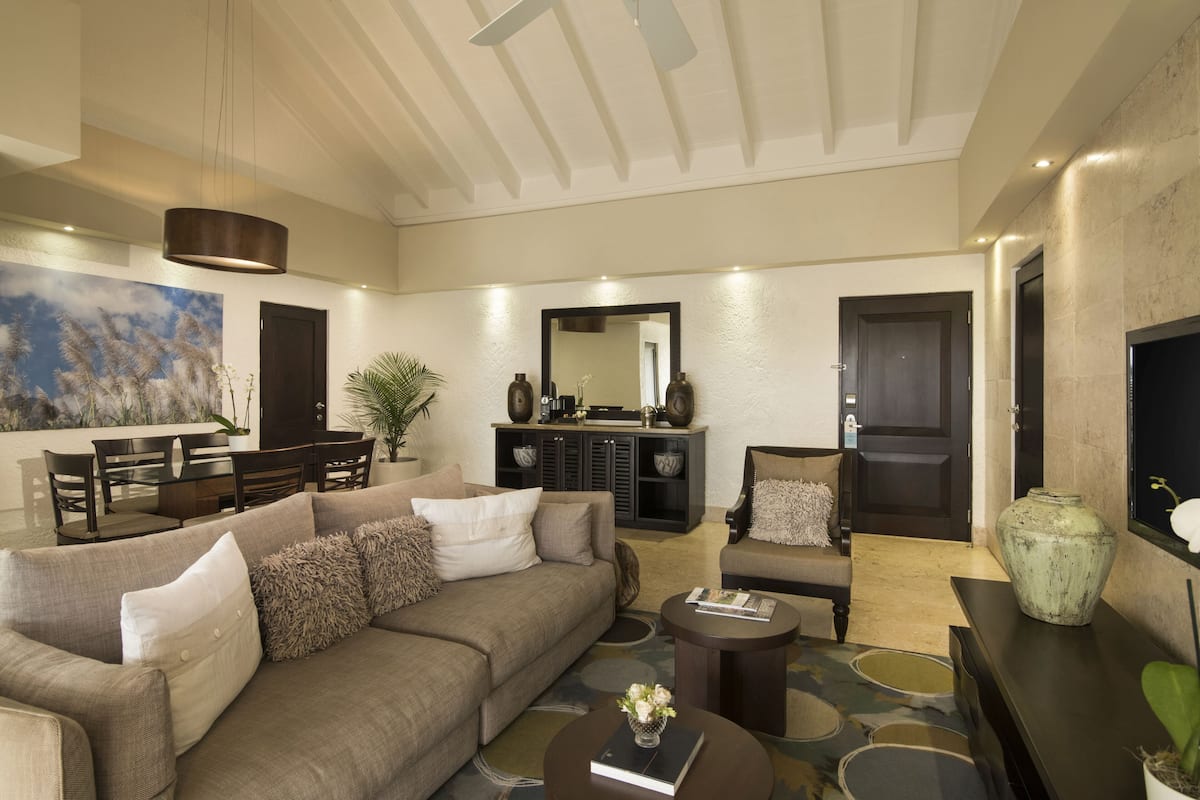 Amplia sala de estar con sofá, sillón, mesa de centro y un comedor con sillas y mesa.