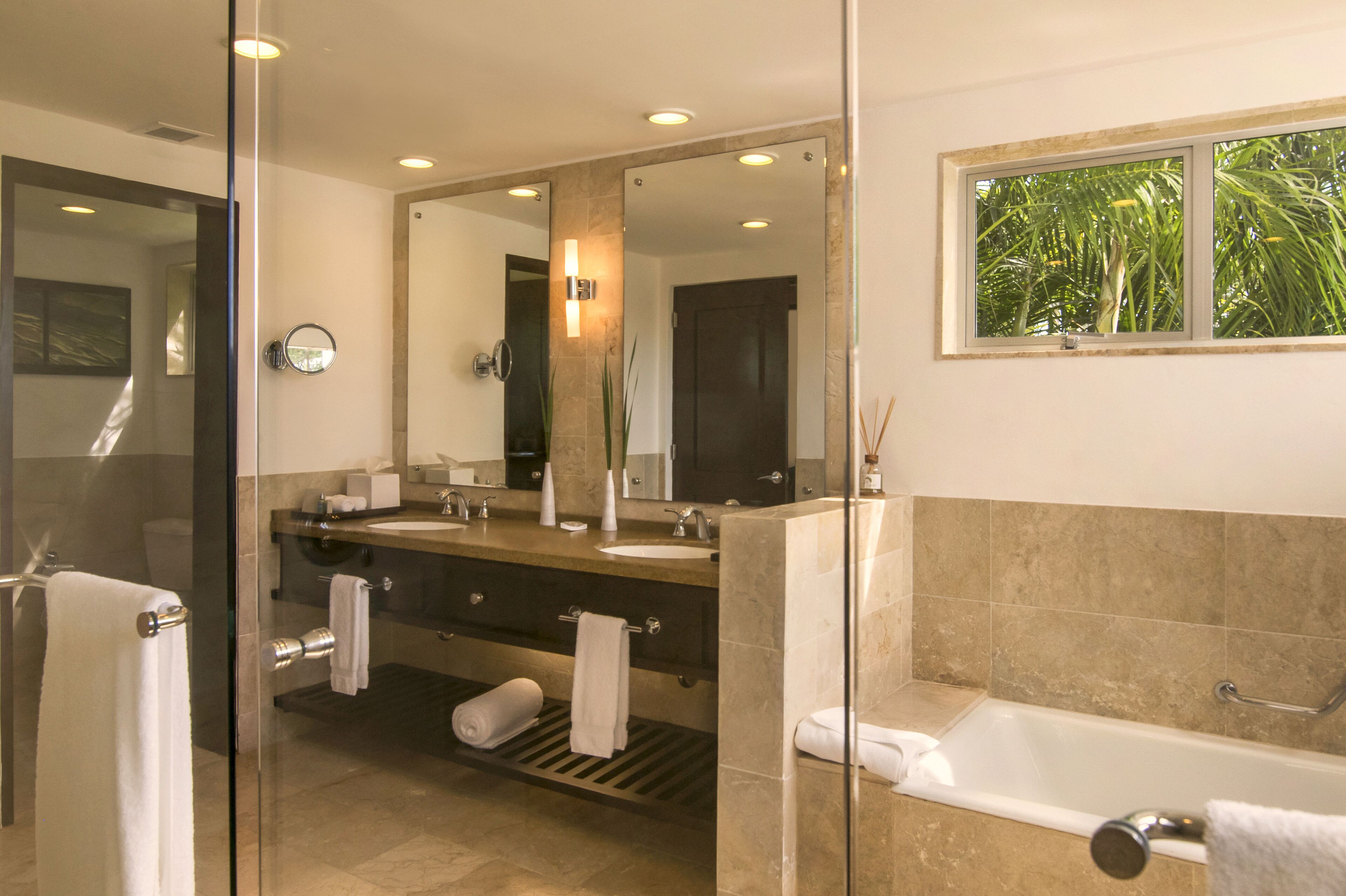 A modern bathroom with a glass shower enclosure, a large mirror, a vanity with a sink, and a bathtub.