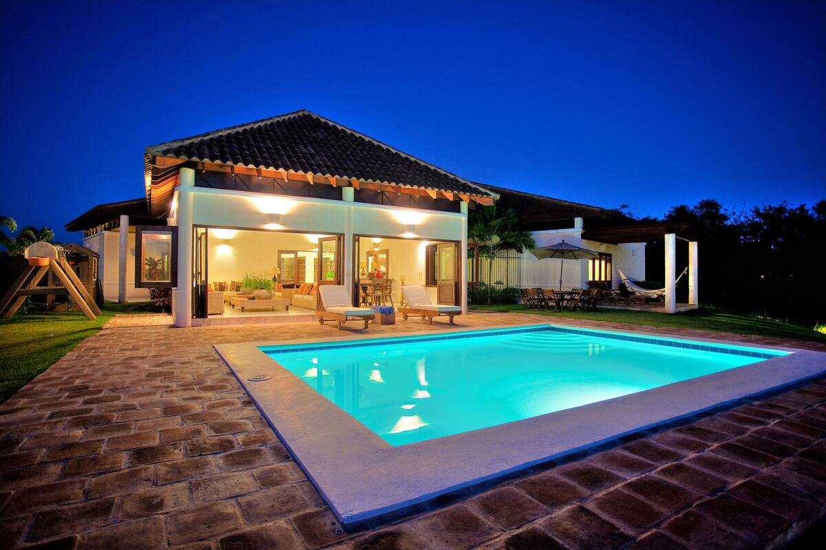 Una casa moderna con piscina, ventanas amplias y un patio.