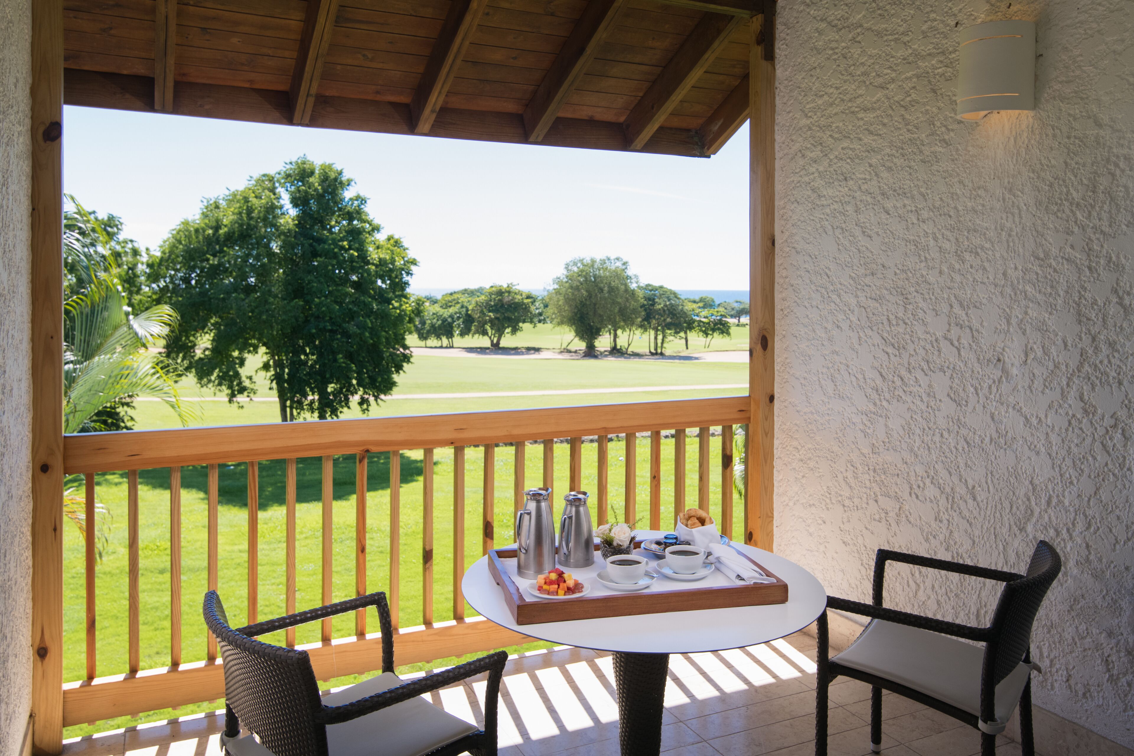 Un balcon avec une table préparée pour le petit-déjeuner, donnant sur un terrain de golf.