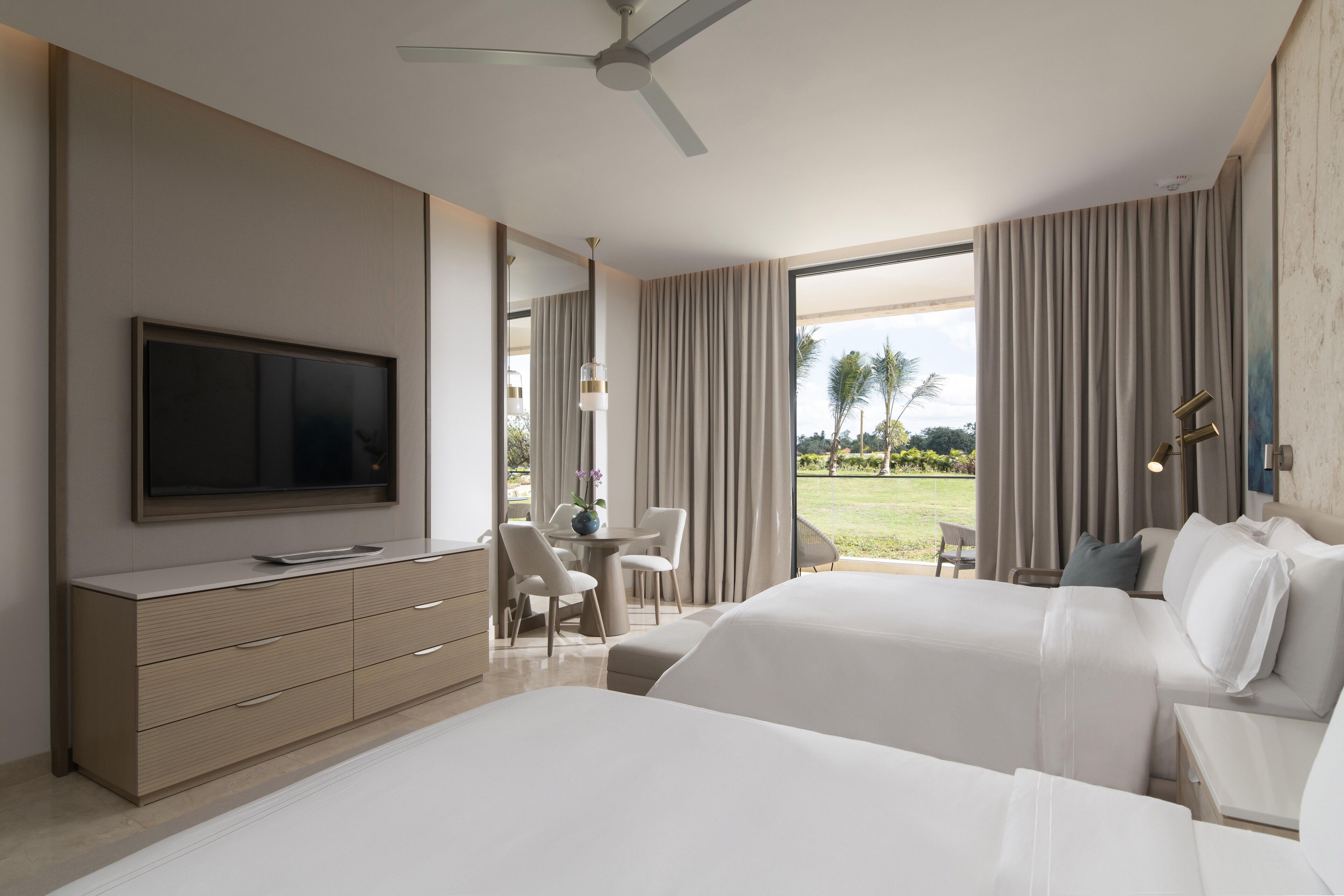 A modern hotel room with a bed, a TV, a desk, and a view of the outdoors.