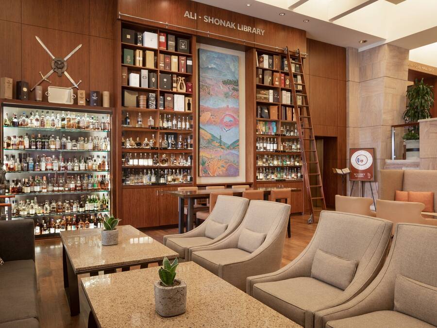 Une bibliothèque avec des étagères, un tableau et des coins salon.