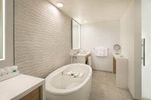 Une salle de bain moderne avec une baignoire sur pieds, un grand miroir et un meuble-lavabo doté d’un évier et d’un porte-serviettes.