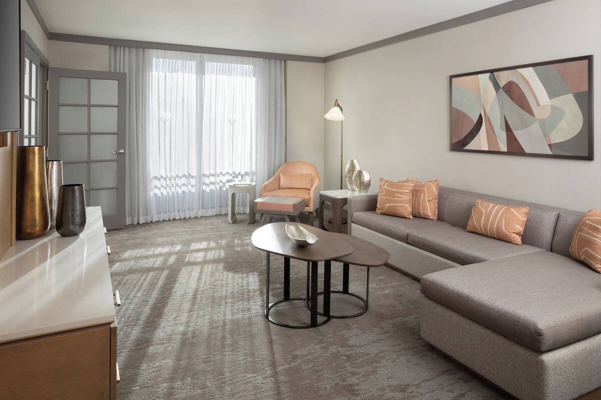 A modern hotel room with a sofa, armchair, and a small table.
