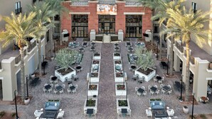 A courtyard with outdoor seating, palm trees, and a central building with a large screen. - The Westin Kierland Resort and Spa (Scottsdale)