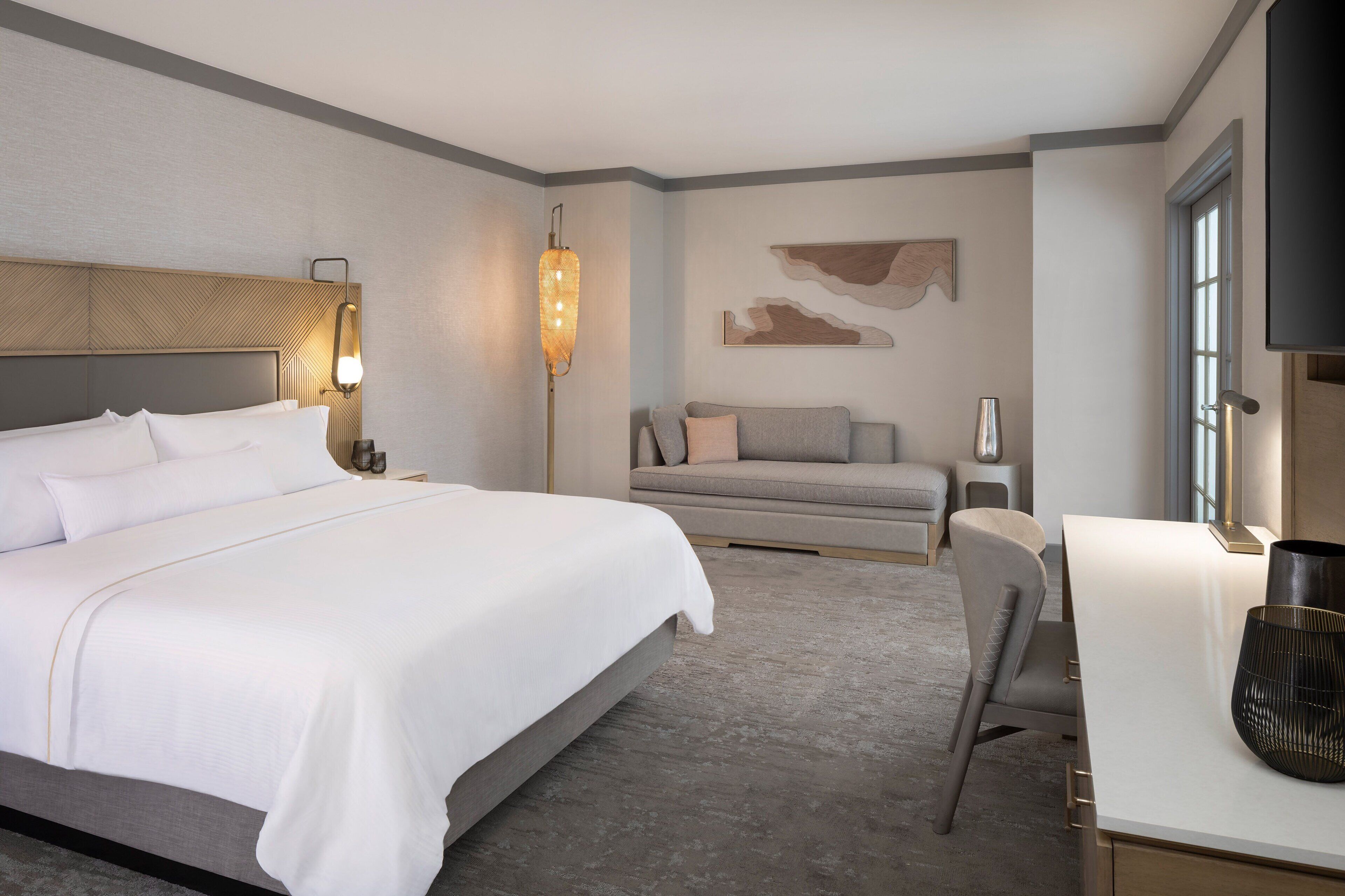 Una habitación de hotel moderna con una cama grande, un escritorio y un sofá.