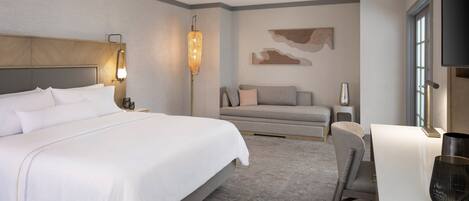 Una habitación de hotel moderna con una cama grande, un escritorio y un sofá.