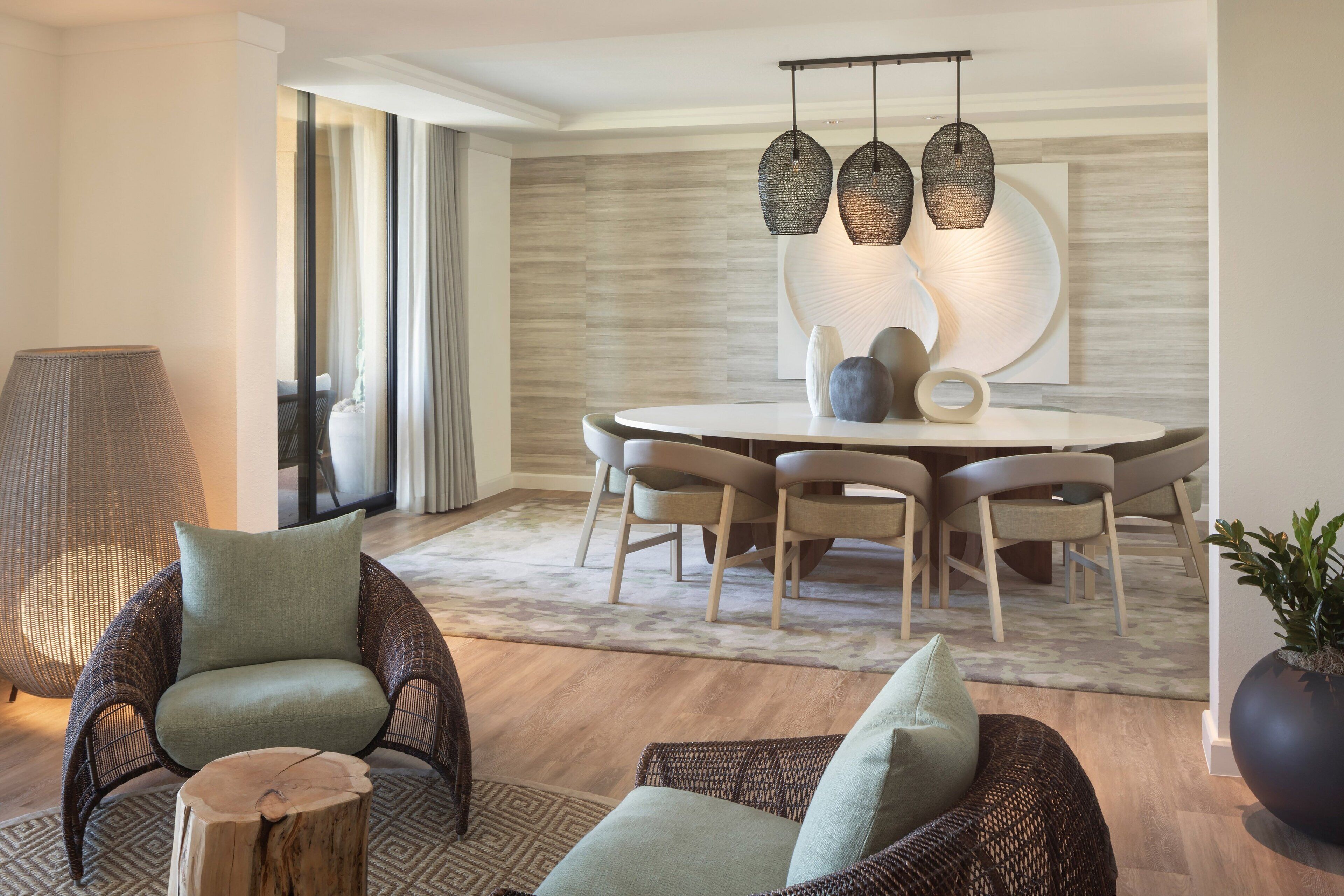 Uma área de jantar moderna com uma mesa redonda, seis cadeiras e luminárias pendentes.