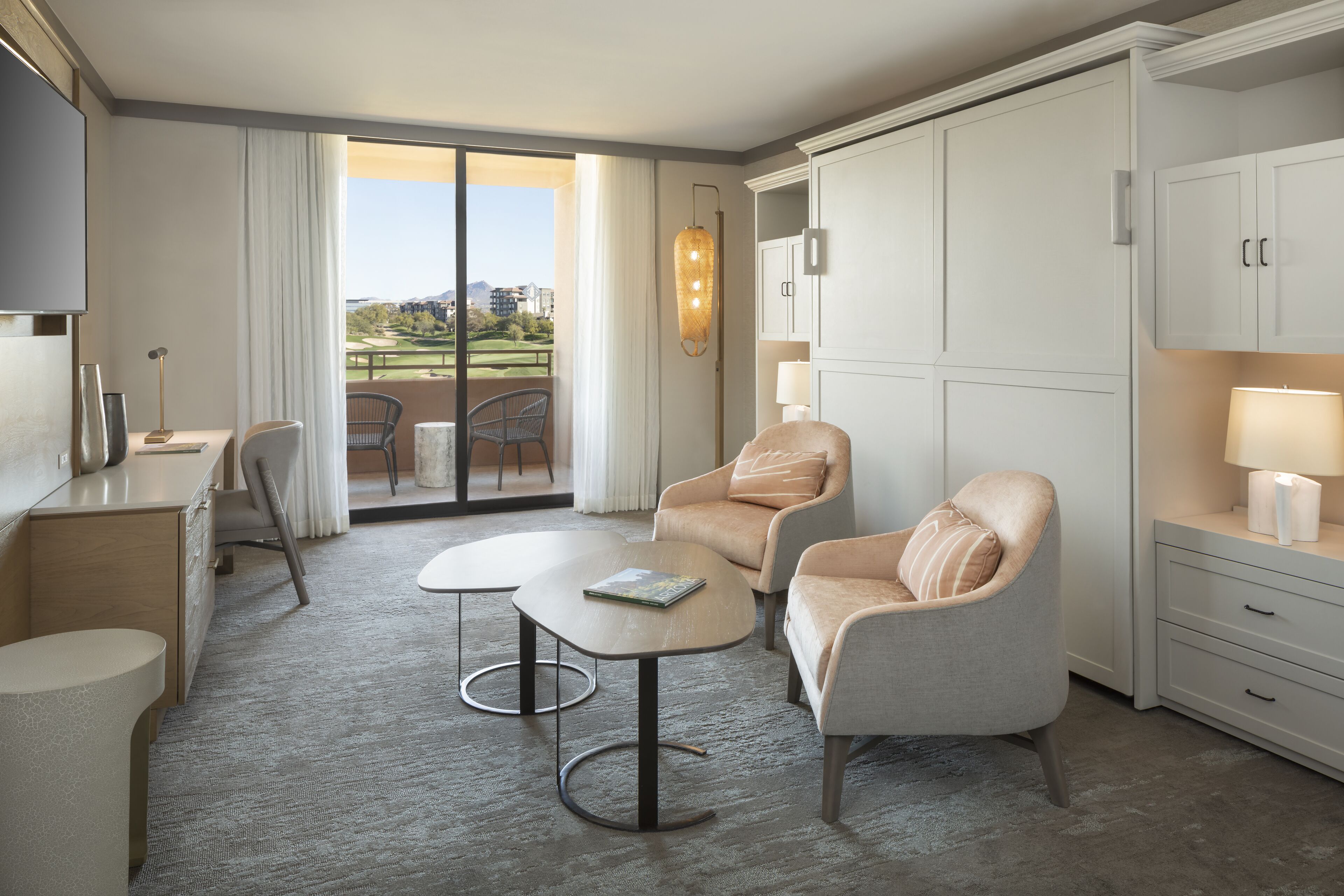 Une chambre d’hôtel moderne dotée d’un balcon, d’un bureau, de deux fauteuils et d’une table à manger.