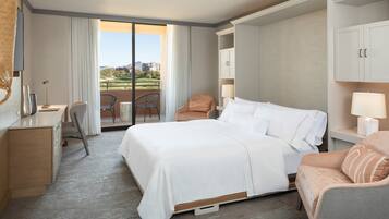 Habitación de hotel con una cama grande, un escritorio, una silla y vista a un campo de golf.