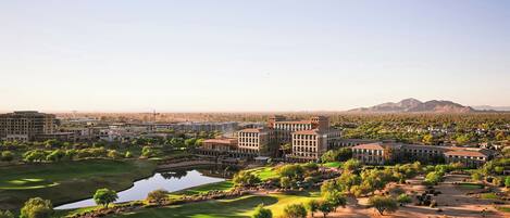 A golf course with a large building complex in the background.