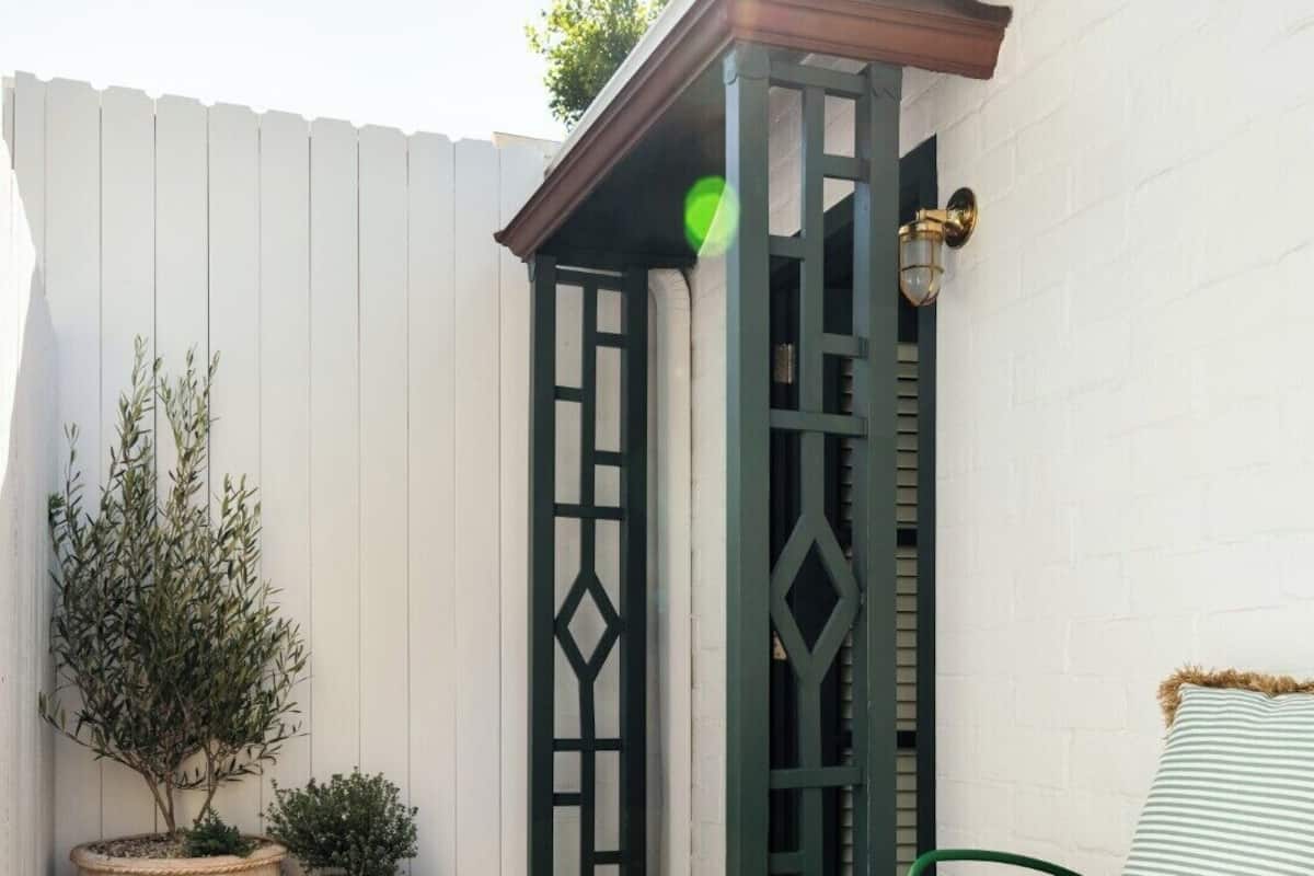 A wooden deck with a green metal chair and a red planter.