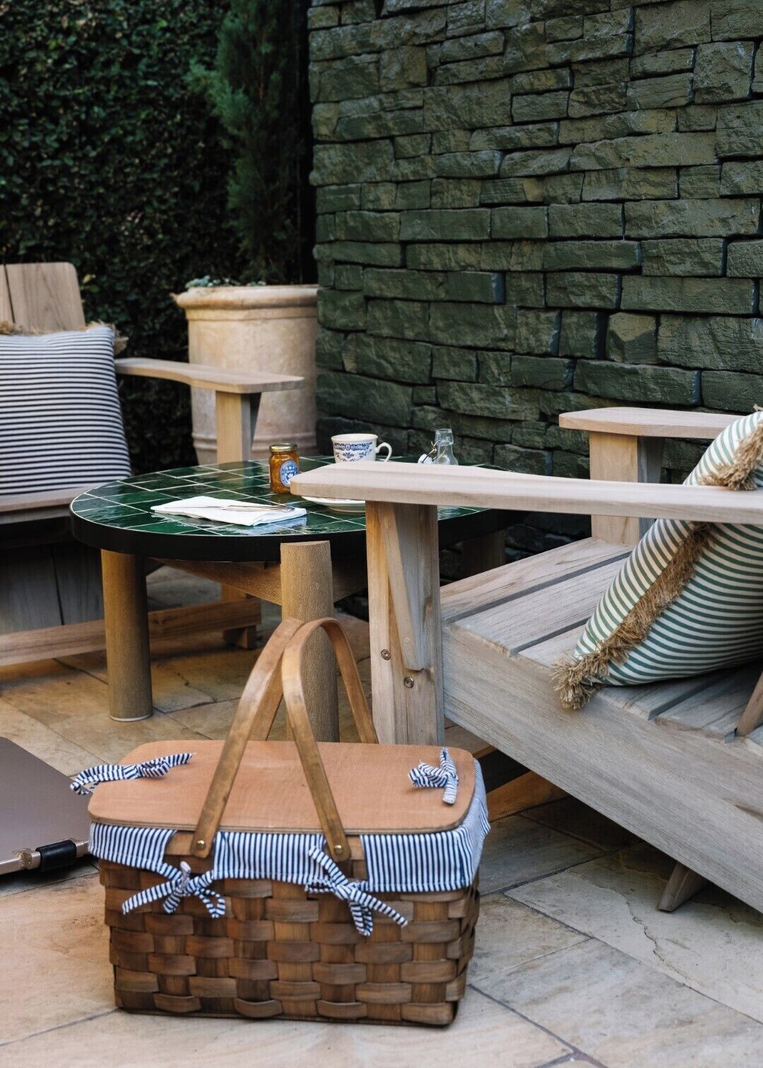An outdoor seating area with a stone wall, a round table, and a cushioned bench.