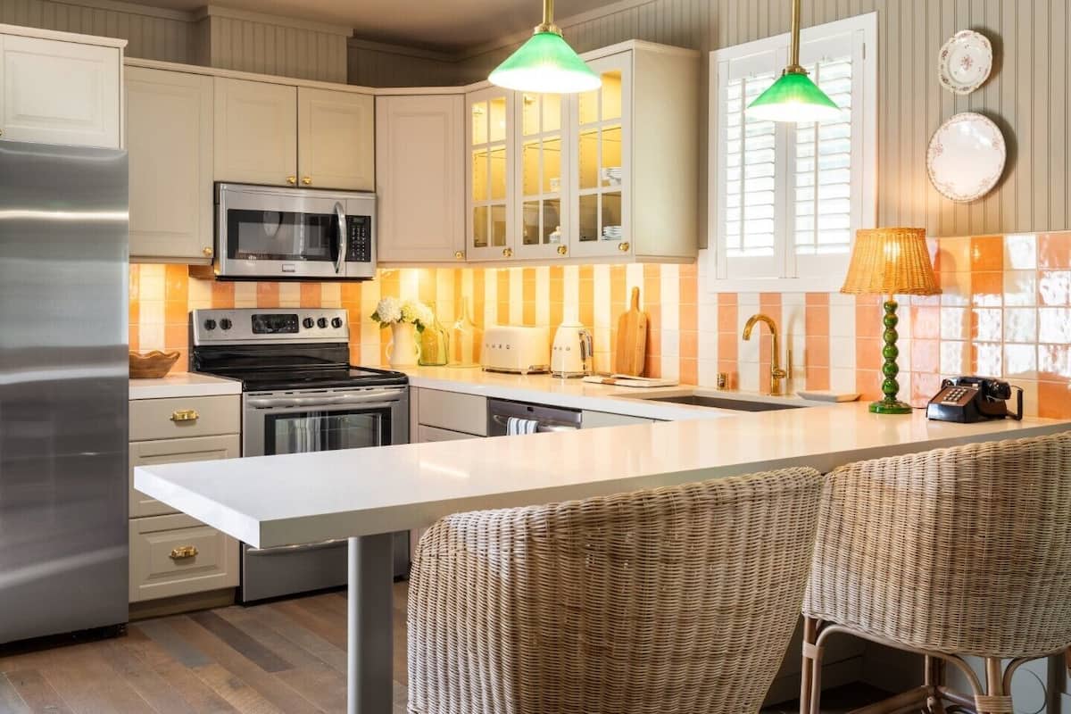 A modern kitchen with white cabinetry, stainless steel appliances, and a central island with bar seating.