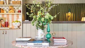 A round table with a vase of flowers, books, and a decorative bowl. - Le Petit Pali Brentwood West Los Angeles (Los Angeles)