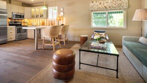 A modern kitchen with a central island, bar stools, and a seating area with a sofa and a glass coffee table. - Le Petit Pali Brentwood West Los Angeles (Los Angeles)